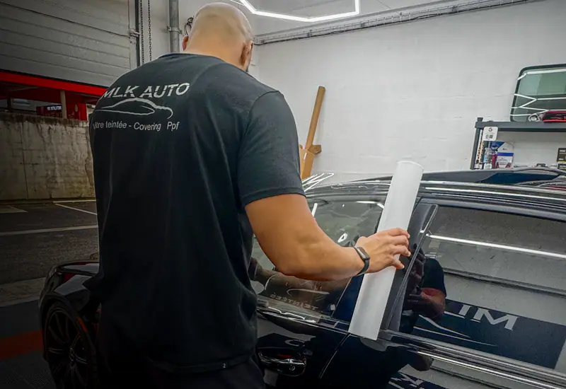 Poseur MLK Auto qui découpe un film solaire sur la vitre d’une voiture