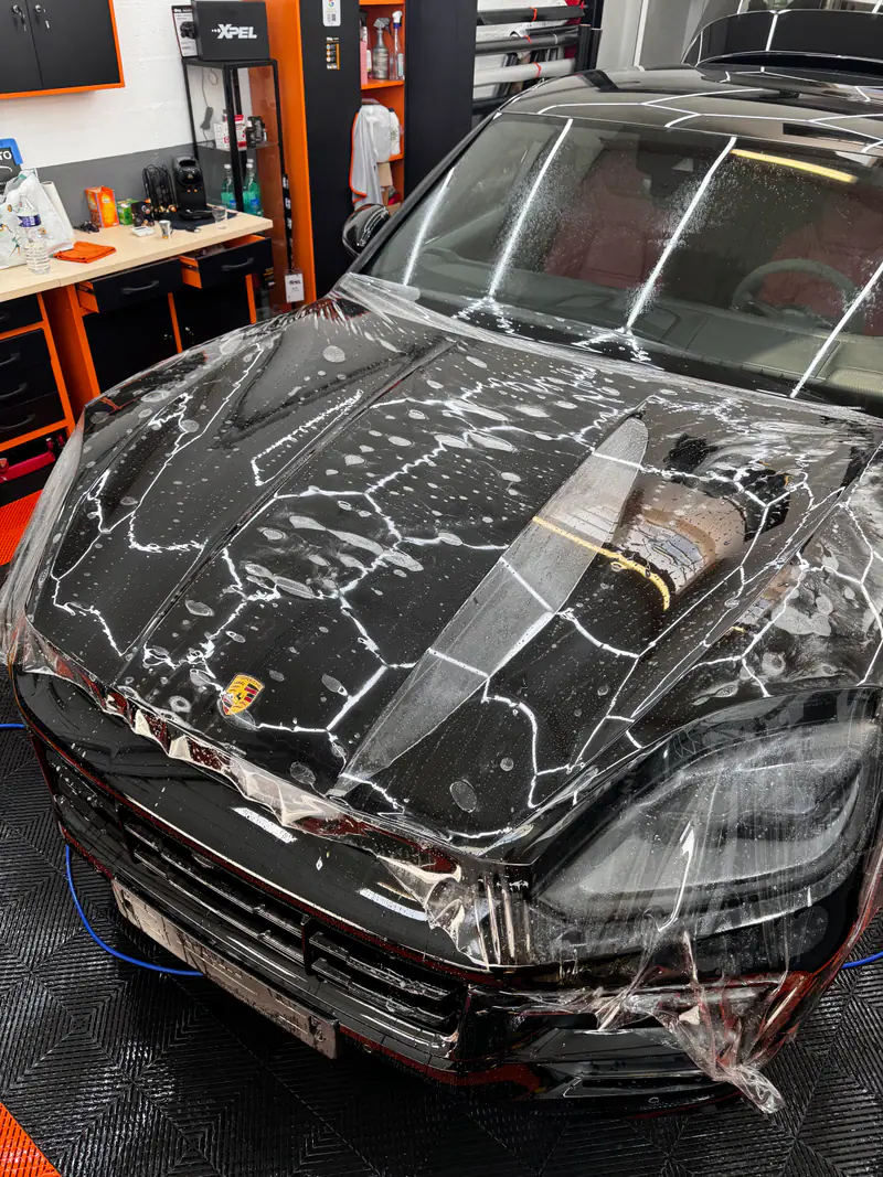 Pose d’un film de protection PPF XPEL sur la face avant d’un Porsche Cayenne à l’atelier MLK Auto